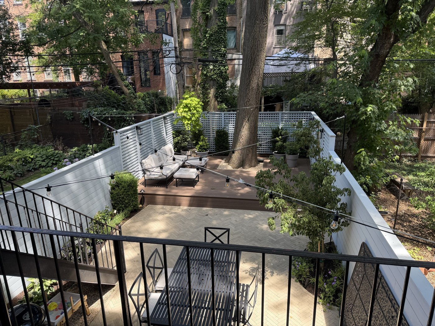 Finished backyard with new deck, paver patio, seating, and string lighting