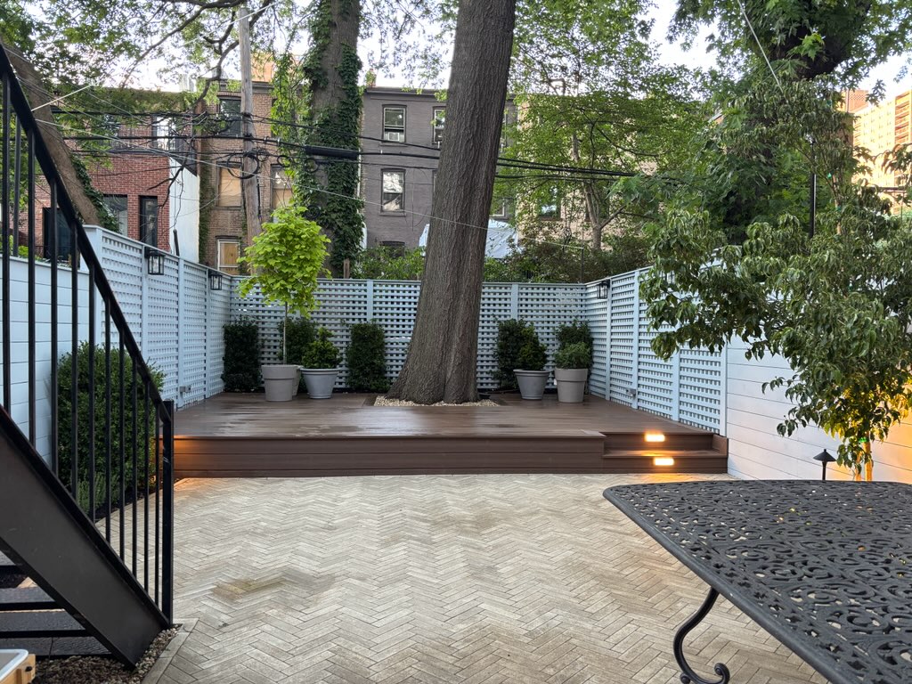 New composite deck and herringbone paver patio around a mature tree
